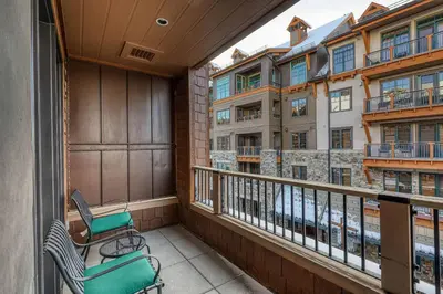 a balcony with a chair and some buildings at Catamount Lodge 312 by East West Hospitality in Truckee