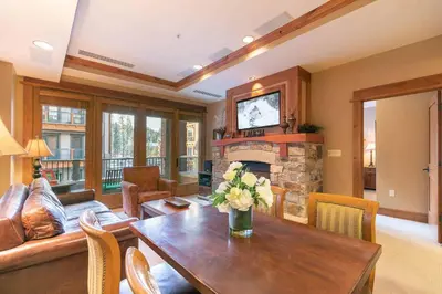a living room with a table and a fireplace at Catamount Lodge 312 by East West Hospitality in Truckee