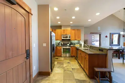 a kitchen with wooden cabinets and a stove top oven at Catamount Lodge 401B by East West Hospitality in Truckee