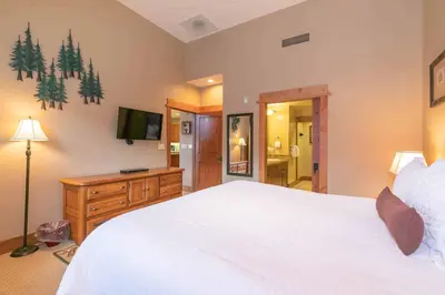a bedroom with a large white bed and a television at Catamount Lodge 404 by East West Hospitality in Truckee