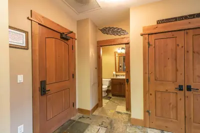 a bathroom with a wooden door and a toilet at Catamount Lodge 404 by East West Hospitality in Truckee