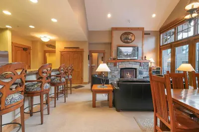a living room with a fireplace and a table and chairs at Catamount Lodge 404 by East West Hospitality in Truckee