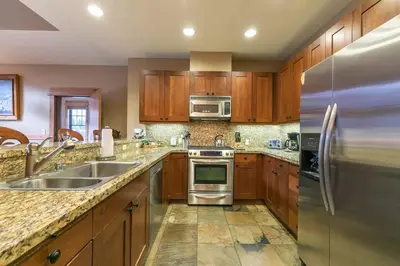 a kitchen with wooden cabinets and stainless steel appliances at Catamount Lodge 404B by East West Hospitality in Truckee