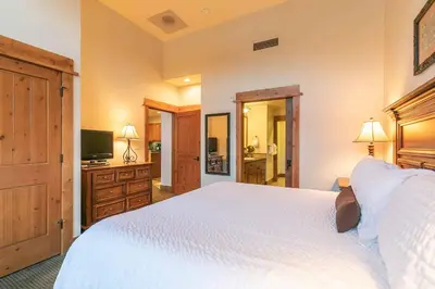 a bedroom with a large white bed and a television at Catamount Lodge 405 by East West Hospitality in Truckee