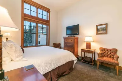 a bedroom with a bed and a tv and a chair at Catamount Lodge 405 by East West Hospitality in Truckee