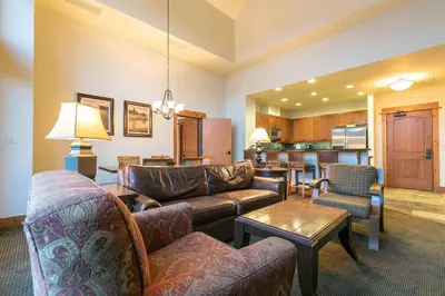a living room with couches and a table and a kitchen at Catamount Lodge 405 by East West Hospitality in Truckee