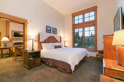 a bedroom with a large bed and a desk with a desk at Catamount Lodge 405A by East West Hospitality in Truckee