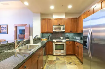 a kitchen with wooden cabinets and a stainless steel refrigerator at Catamount Lodge 405B by East West Hospitality in Truckee