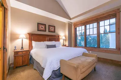 a bedroom with a large bed and a chair at Catamount Lodge 409 by East West Hospitality in Truckee