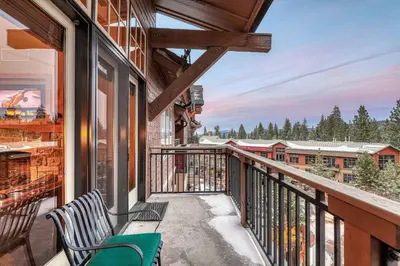 a balcony with two chairs and a view at Catamount Lodge 409 by East West Hospitality in Truckee