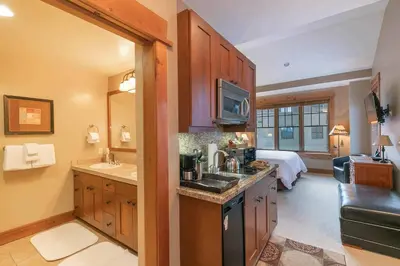 a kitchen with a sink and a bedroom with a bed at Catamount Lodge 404A by East West Hospitality in Truckee