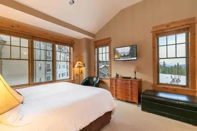 a bedroom with a large bed and windows at Catamount Lodge 404A by East West Hospitality in Truckee