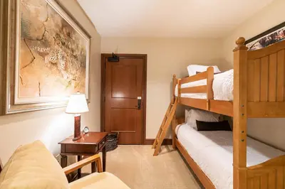 a bedroom with two bunk beds and a desk with a lamp at Great Bear Lodge 201 by East West Hospitality in Truckee