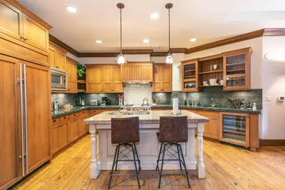 a kitchen with wooden cabinets and a island with bar stools at Great Bear Lodge 302 by East West Hospitality in Truckee