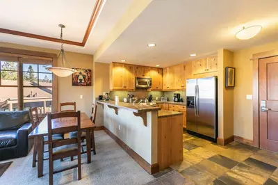 a kitchen with a table and a refrigerator at Iron Horse Lodge North 209 by East West Hospitality in Truckee