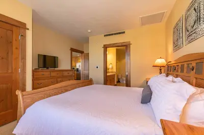 a bedroom with a large white bed and a television at Iron Horse Lodge North 209 by East West Hospitality in Truckee