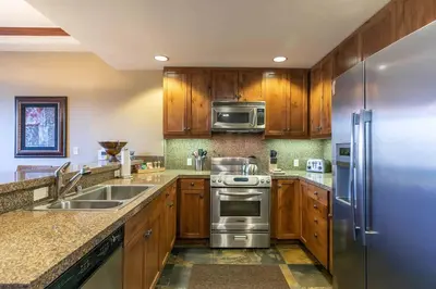 a kitchen with wooden cabinets and a stainless steel refrigerator at Iron Horse Lodge South 305 by East West Hospitality in Truckee