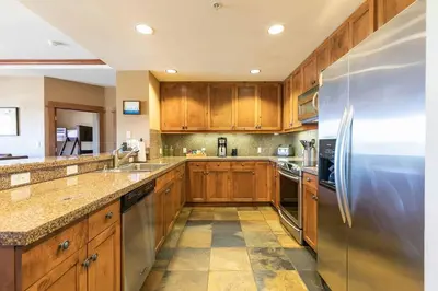 a kitchen with wooden cabinets and a stainless steel refrigerator at Iron Horse Lodge North 205 by East West Hospitality in Truckee