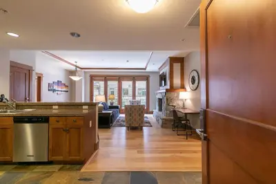 a kitchen with wooden cabinets and a living room at Iron Horse Lodge North 206 by East West Hospitality in Truckee