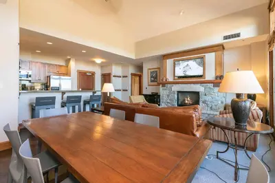 a living room with a wooden table and a fireplace at Iron Horse Lodge North 305 by East West Hospitality in Truckee