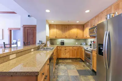 a kitchen with wooden cabinets and a stainless steel refrigerator at Iron Horse Lodge South 404 by East West Hospitality in Truckee
