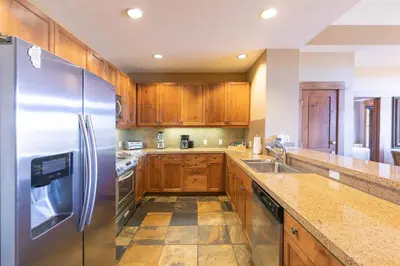 a kitchen with wooden cabinets and a stainless steel refrigerator at Iron Horse Lodge North 307 by East West Hospitality in Truckee