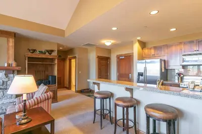 a kitchen with wooden cabinets and bar stools at Iron Horse Lodge North 307 by East West Hospitality in Truckee