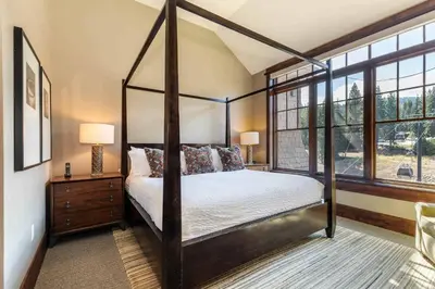 a bedroom with a four poster bed and windows at One Village Place 508 by East West Hospitality in Truckee
