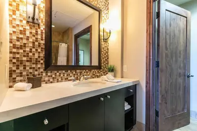 a bathroom with a sink and a mirror at One Village Place 502 by East West Hospitality in Truckee
