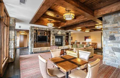 a living room with a table and a stone wall at Ski Trails 4115 by East West Hospitality in Truckee