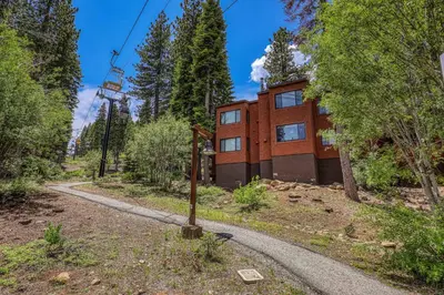 a house on a hill with a winding road at Ski Trails 4099 by East West Hospitality in Truckee