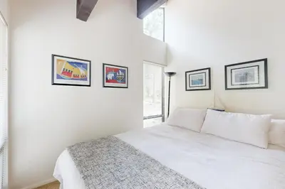 a white bedroom with a bed and some pictures on the wall at Kingswood Village #167 in Kings Beach
