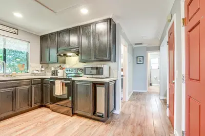 a kitchen with brown cabinets and a wooden floor at Downtown Fair Oaks Home about 15 Mi to Sacramento! in Fair Oaks