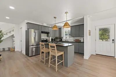 a kitchen with gray cabinets and a island with chairs at The River House in Three Rivers