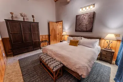 a bedroom with a large bed and a wooden cabinet at Peppermint Falls Ranch in Ponderosa