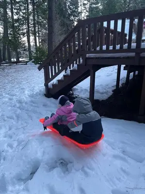 a couple of children riding on a sled in the snow at Cozy Chalet - Hot Tub with Meadow Views - Family & Pets, Fire Pit & BBQ in Arnold