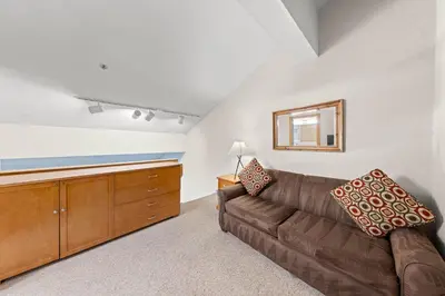a living room with a brown couch and a mirror at Palisades Tahoe Lodge Rentals Studio Loft #356 in Olympic Valley