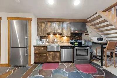 a kitchen with wooden cabinets and stainless steel appliances at Palisades Tahoe Lodge Rentals Studio Loft #344 in Olympic Valley