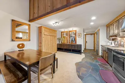 a kitchen with a wooden table and a dining room at Palisades Tahoe Lodge Rentals Studio Loft #344 in Olympic Valley