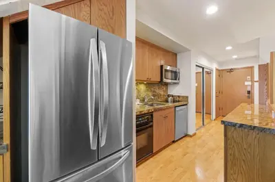 a stainless steel refrigerator in a kitchen with wooden cabinets at Palisades Tahoe Lodge Rentals Studio Loft #338 in Olympic Valley