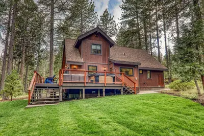 a large house with a large deck in the woods at Eclipse Retreat at Tahoe Park - Hot Tub - Fenced Yard & steps to HOA Access in Tahoe City