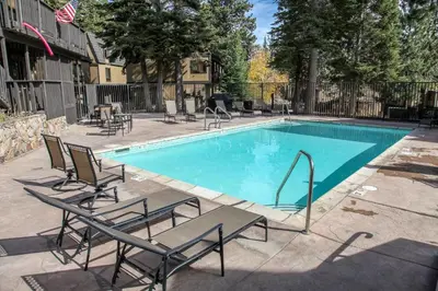 a swimming pool with chaise lounge chairs next to it at Bigwood #45 condo in Mammoth Lakes