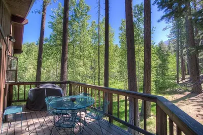 a deck with a table and chairs on a porch with trees at Aspen View Lodge home in South Lake Tahoe