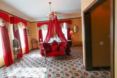 a room with a red chair and a chandelier at Mizpah Hotel in Tonopah