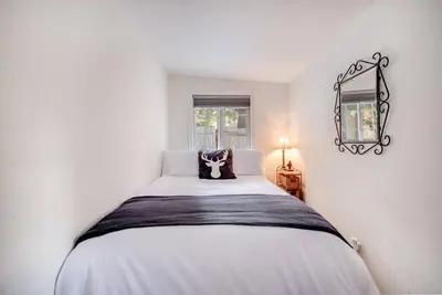 a bedroom with a large white bed with a mirror at Alpine Cottage Hideaway in Stateline