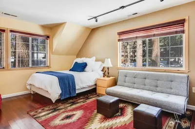 a bedroom with a bed and a couch and windows at Alpine Cottage Hideaway in Stateline