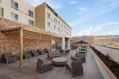 a hotel patio with chairs and tables and an umbrella at Courtyard by Marriott Reno Sparks in Clark