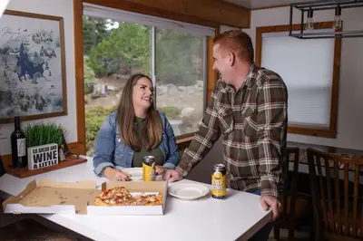 a man and a woman standing at a table with a box of pizza at Buckeye Bear's Den-AC-Walking Distance to town in Shaver Lake