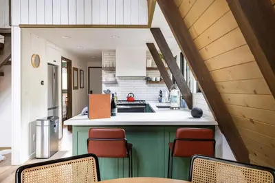 an attic kitchen with a green island with chairs at Dogwood Peak Mid-Century A-Frame with AC Style in Shaver Lake