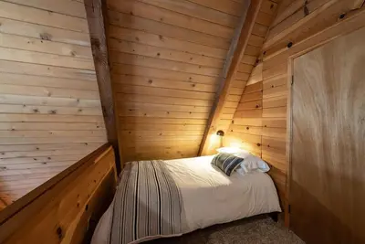 a small room with a bed in a wooden cabin at HB Hideaway Boho Treehouse Vibes in the Pines in Shaver Lake